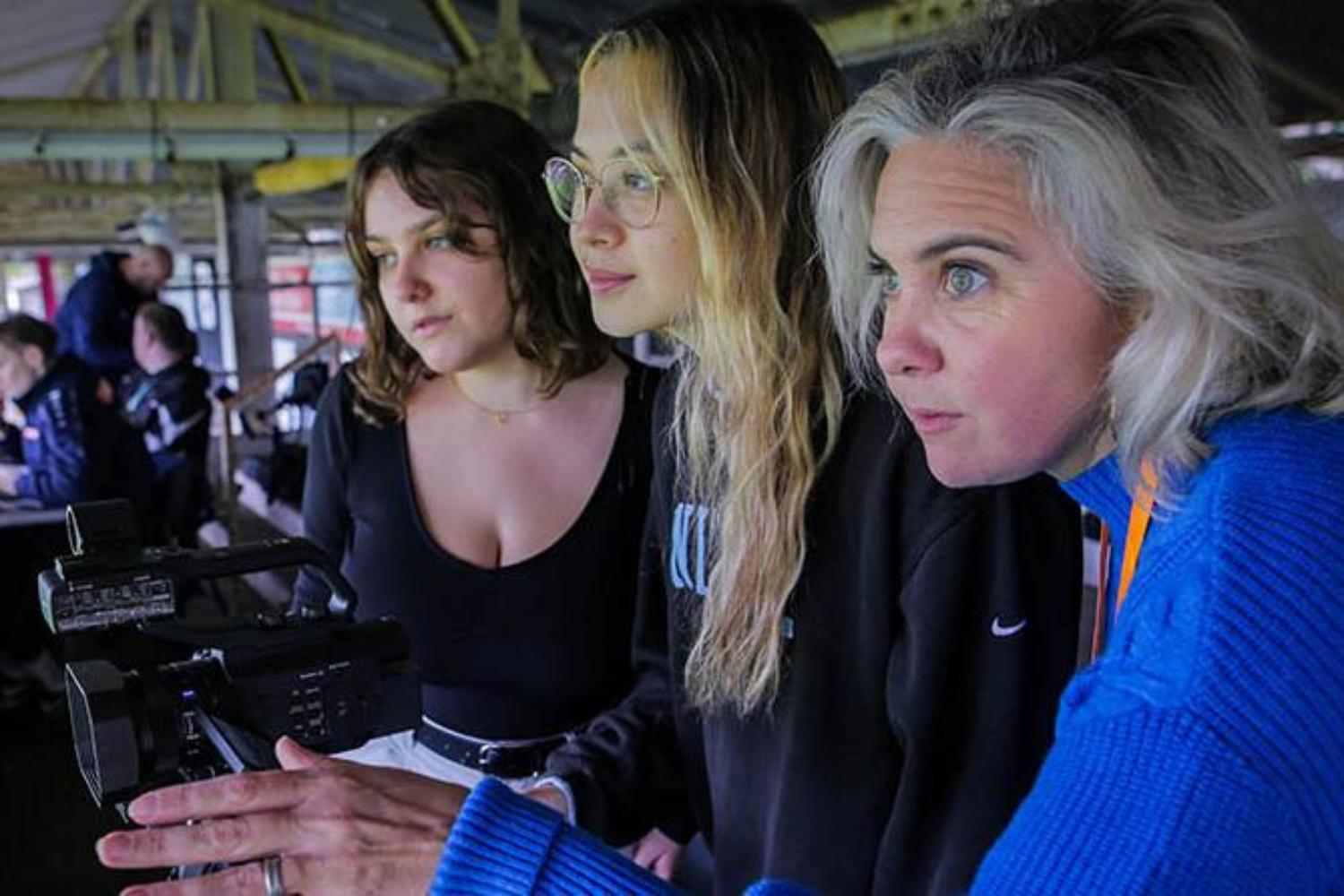 A group of women filming in a sports stadium
