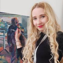 Lauren White posing in front of one of her paintings